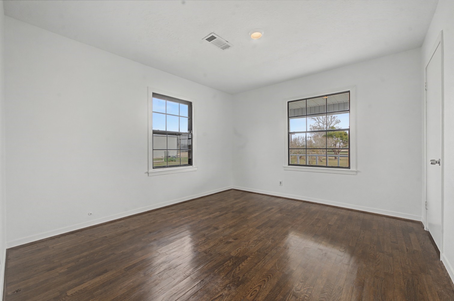 14077 Hamshire Road Hamshire, TX 77622 - Photo 24 of 39 This room features hardwood like floors, neutral walls, and two large windows for ample natural light, offering a bright and welcoming space.