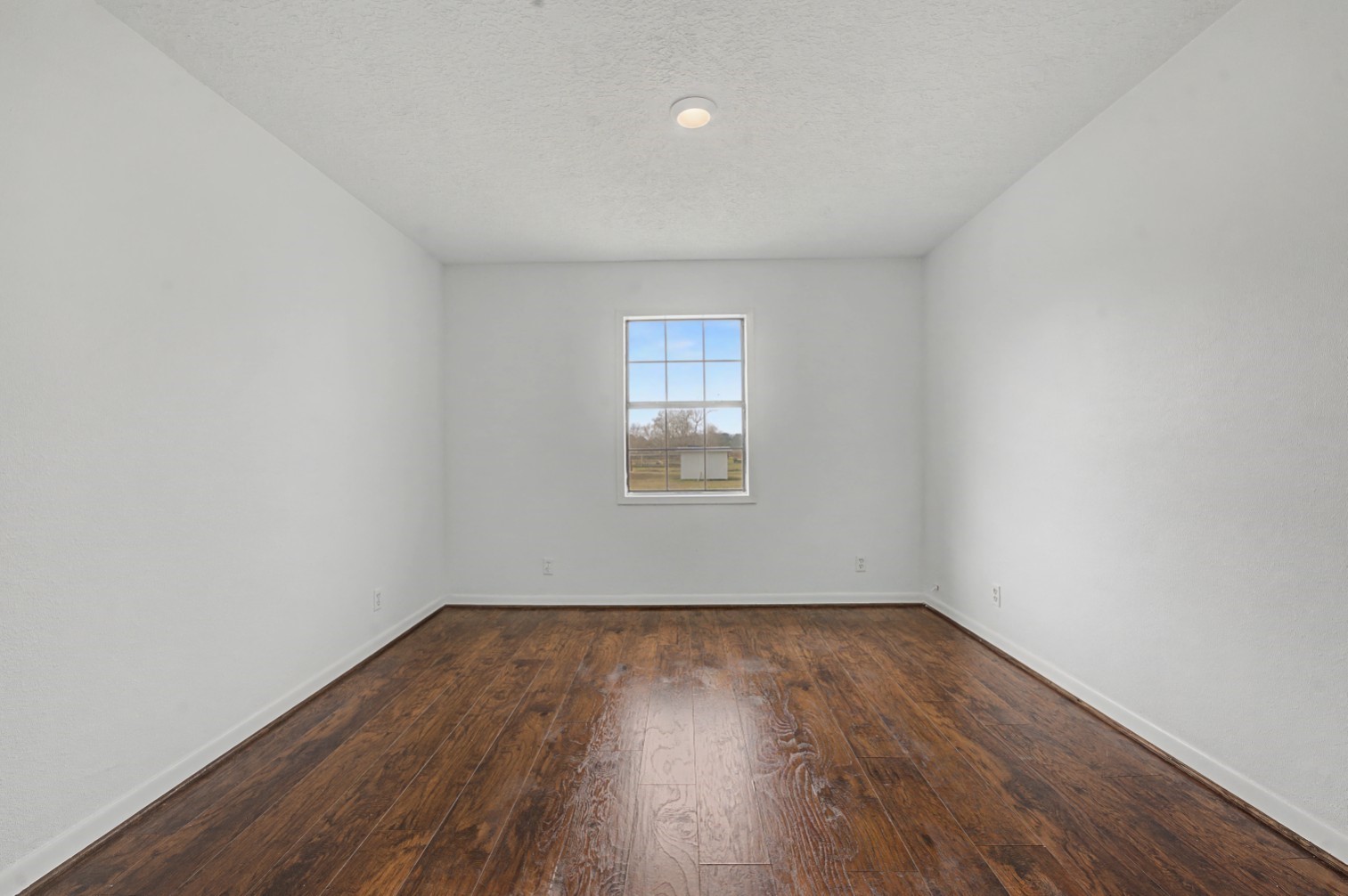 14077 Hamshire Road Hamshire, TX 77622 - Photo 27 of 39 This room features crisp white walls and rich flooring, complemented by a central window that allows natural light to fill the space, creating a bright and welcoming atmosphere.