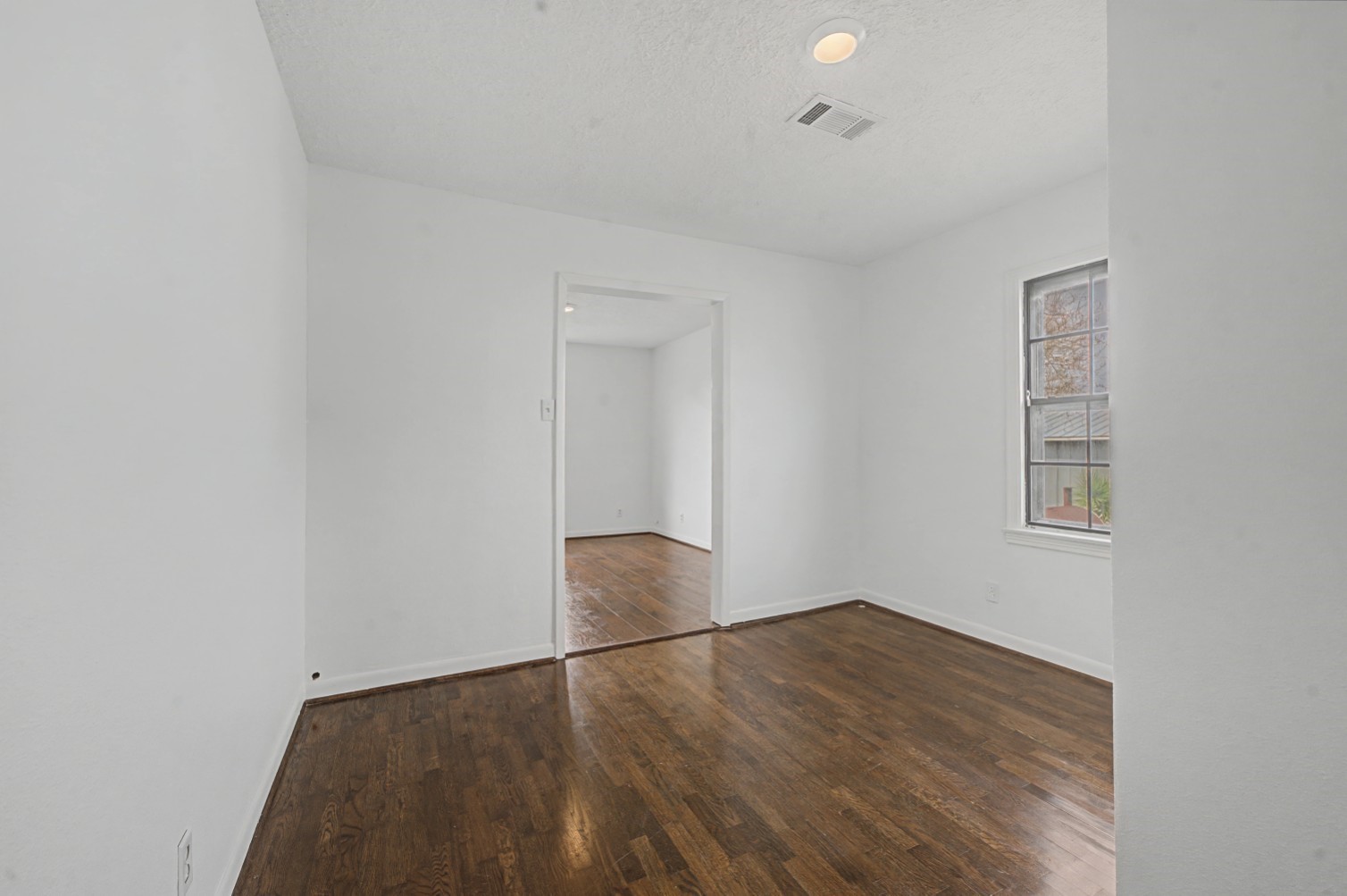 14077 Hamshire Road Hamshire, TX 77622 - Photo 28 of 39 This photo shows a bright room with white walls and polished floors. It features a window allowing natural light and a doorway leading to another room. The ceiling has recessed lighting and a vent, providing a clean and modern look.