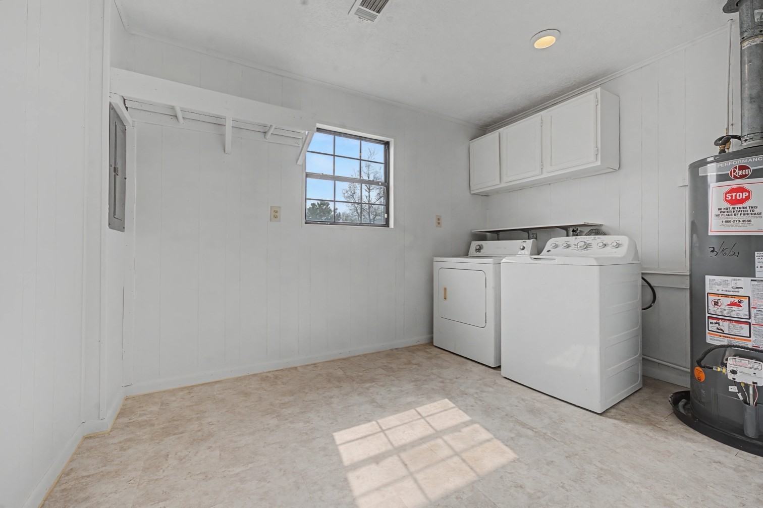 14077 Hamshire Road Hamshire, TX 77622 - Photo 29 of 39 Bright laundry room with white walls and cabinetry, featuring a washer, dryer, and water heater. A window provides natural light, and there's ample space for storage.