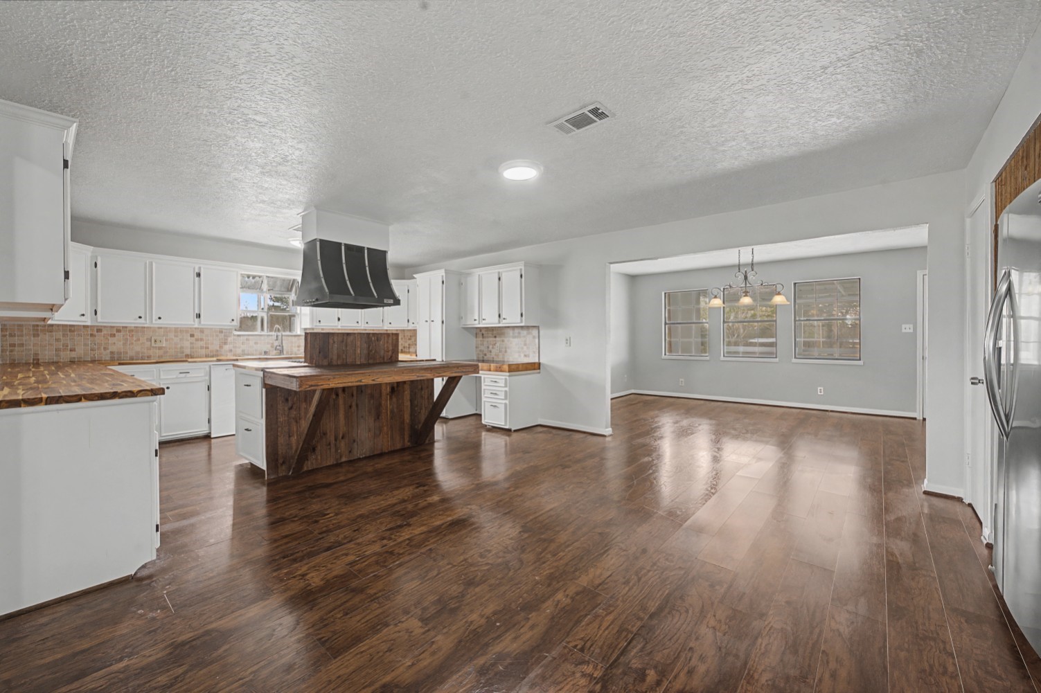 14077 Hamshire Road Hamshire, TX 77622 - Photo 6 of 39 This spacious kitchen and dining area features elegant floors, white cabinetry, and a rustic central island. The open layout is perfect for entertaining, while large windows provide ample natural light.
