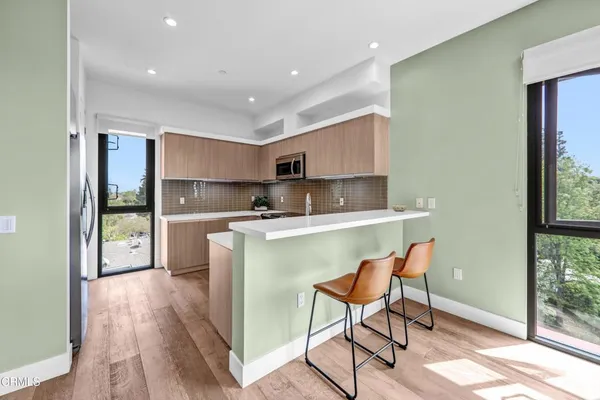 a kitchen with kitchen island a sink a stove a refrigerator cabinets and a dining table