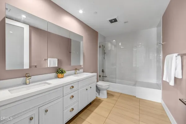 a spacious bathroom with a granite countertop sink a toilet a mirror and shower