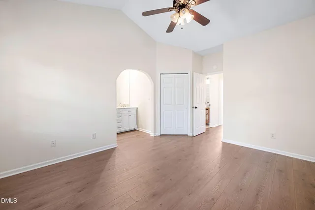 an empty room with wooden floor chandelier fan and windows