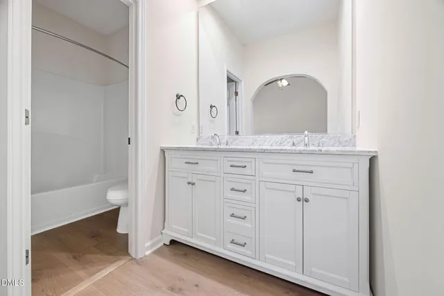 an empty room with wooden floor chandelier fan and windows