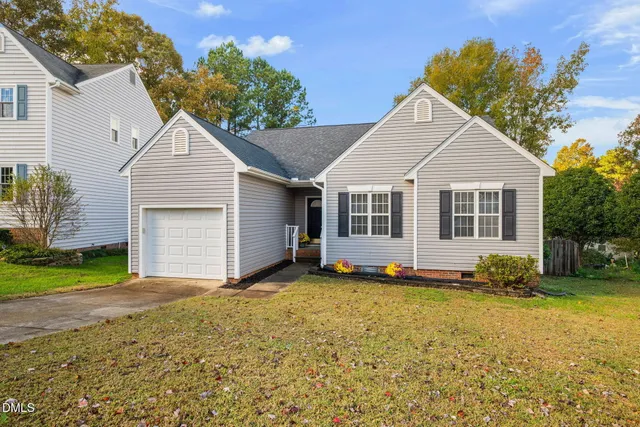 a view of a house with a yard and large tree