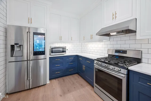 a kitchen with stainless steel appliances granite countertop a refrigerator and a stove top oven