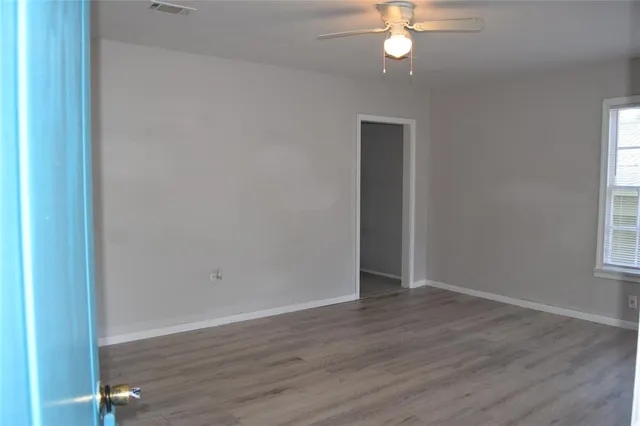 a view of empty room with wooden floor and fan