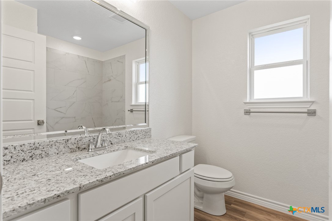1204 Victory Ranch Trail Killeen, TX 76549 - Photo 24 of 33 a bathroom with a granite countertop sink a toilet and a mirror