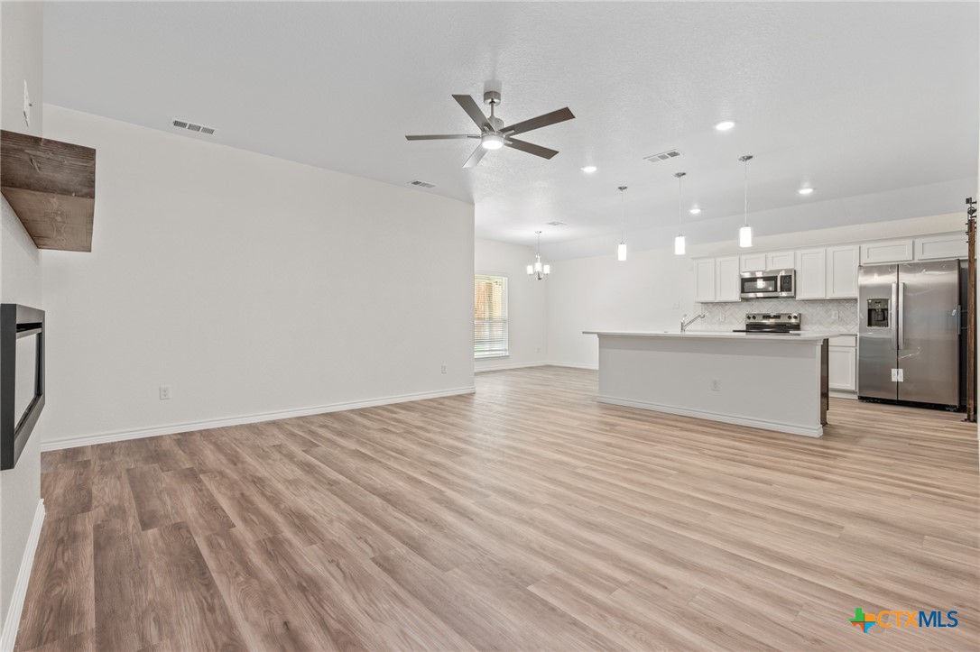 1204 Victory Ranch Trail Killeen, TX 76549 - Photo 6 of 33 a view of an empty room with wooden floor and a ceiling fan
