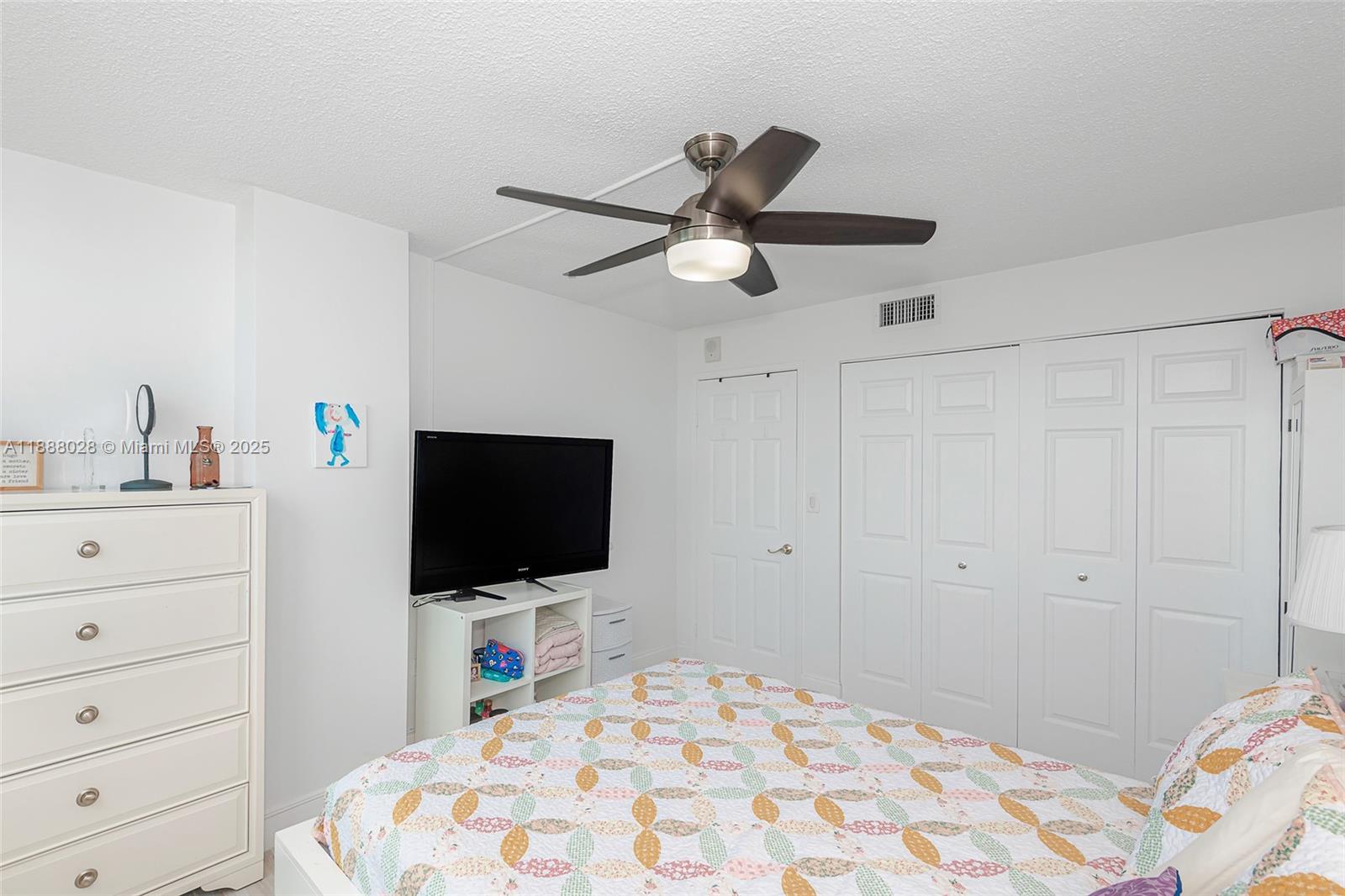 7135 Collins Avenue, Unit 625 Miami Beach, FL 33141 - Photo 26 of 33 a bedroom with a bed and a flat tv screen on dresser