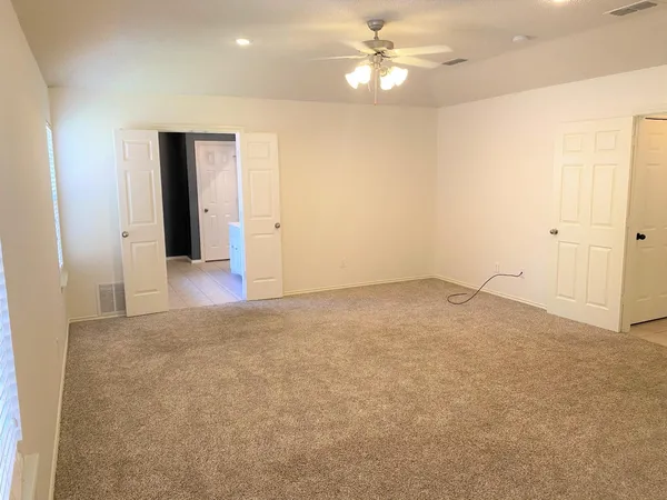 an empty room with closet and a ceiling fan