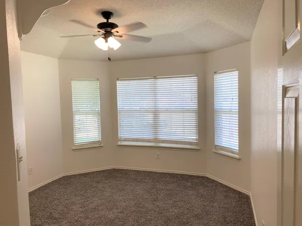 an empty room with chandelier fan and windows
