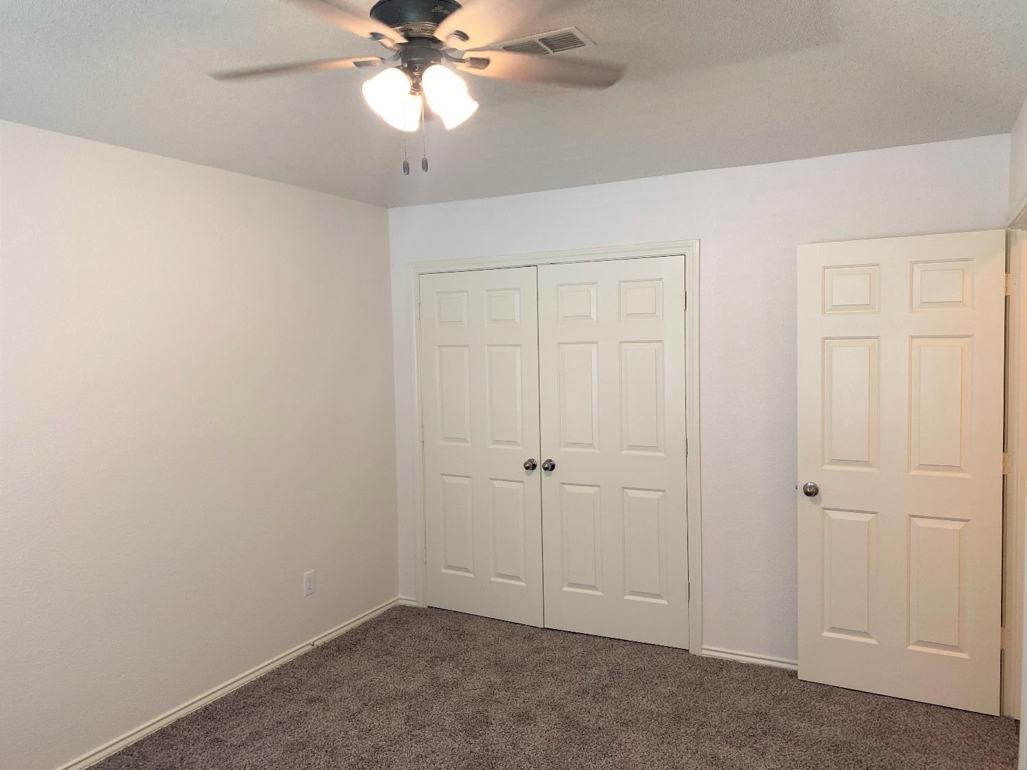 6521 8th Street Lubbock, TX 79416 - Photo 10 of 25 an empty room with a chandelier fan