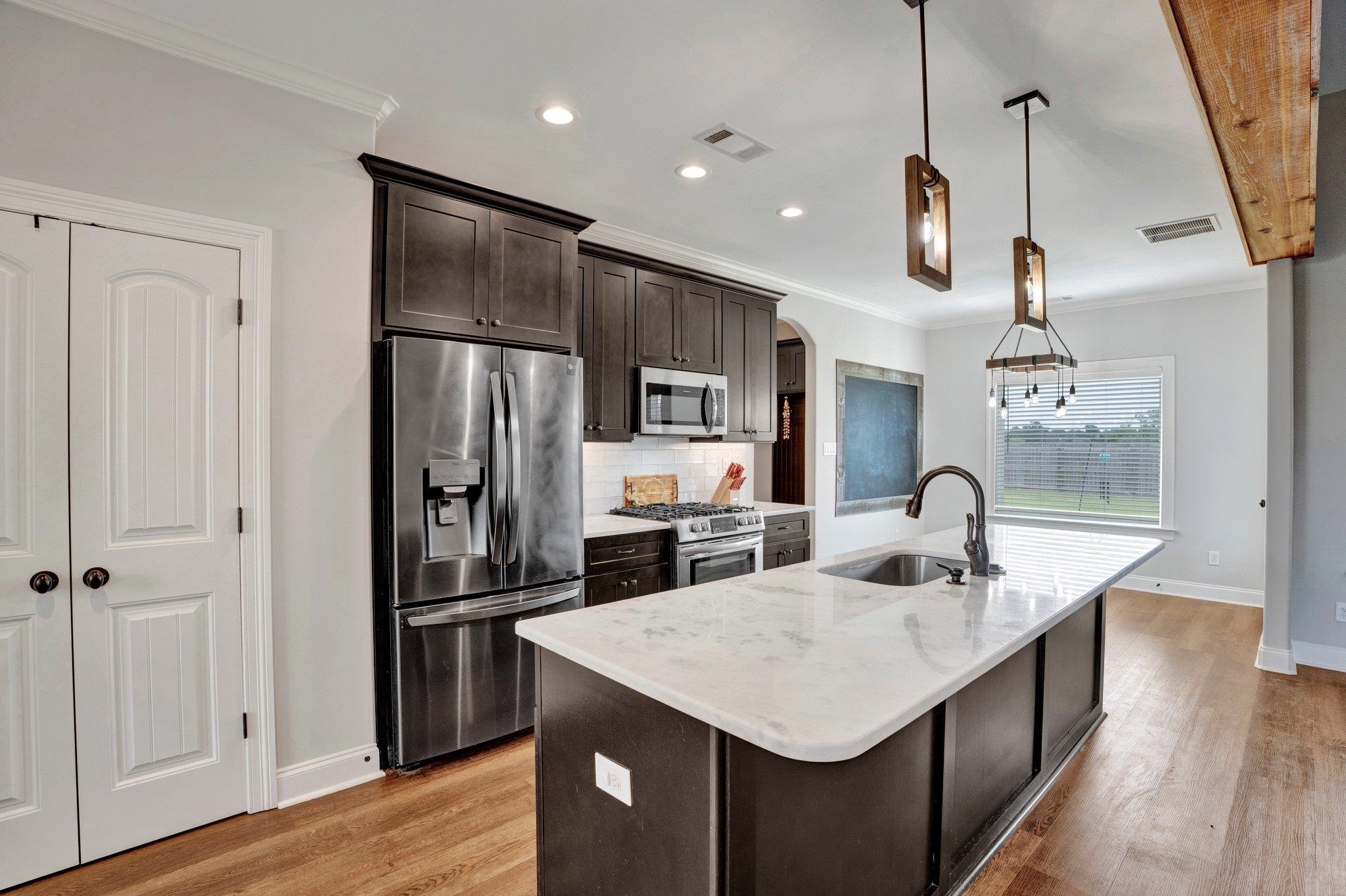21 Trinity Cove Atoka, TN 38004 - Photo 8 of 21 a kitchen with a refrigerator a sink dishwasher a oven and a dining table with wooden floor