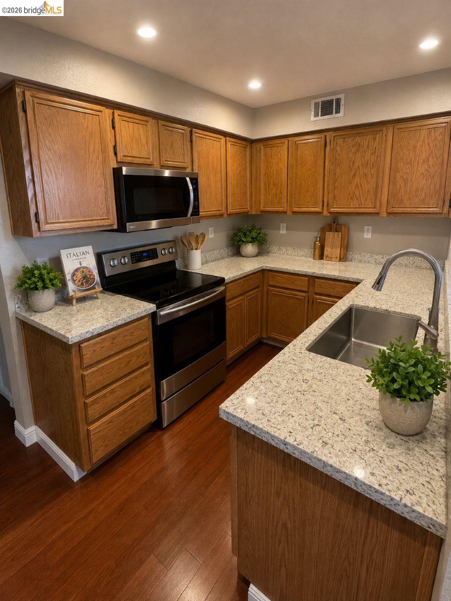 3623 Wells Road Oakley, CA 94561 - Photo 12 of 59 U-shaped kitchen featuring wood cabinetry, granite-style countertops, wood-finish flooring, a stainless steel sink, and stainless steel appliances