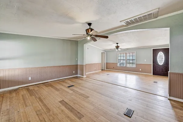 a view of an empty room with a window and wooden floor