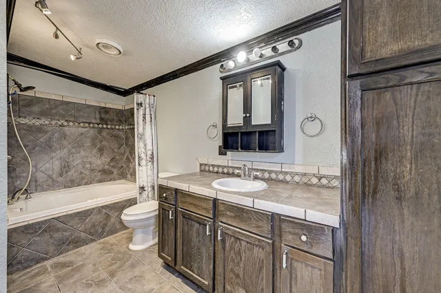 a bathroom with a bathtub shower sink mirror and toilet