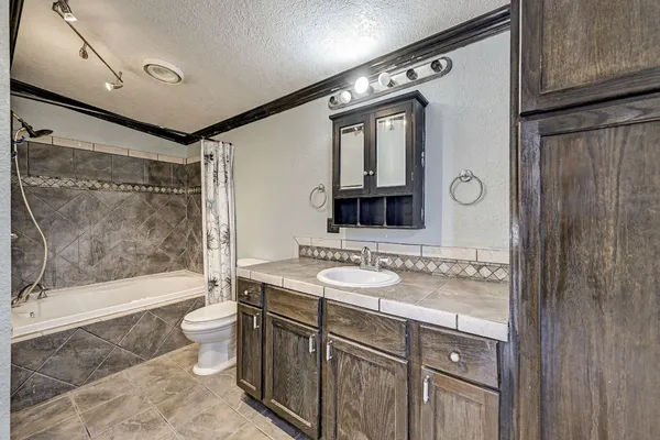 a bathroom with a bathtub shower sink mirror and toilet