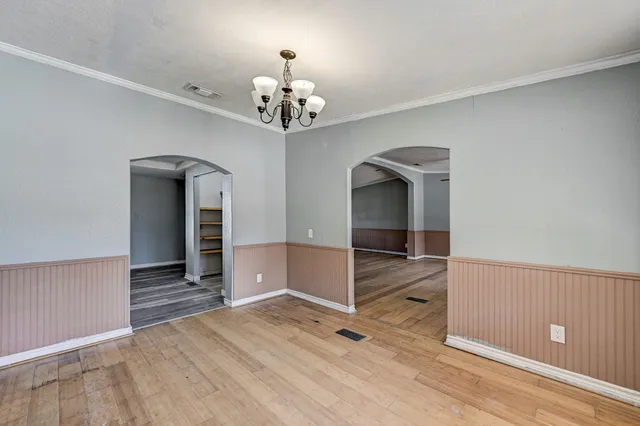 wooden floor in an empty room with a chandelier