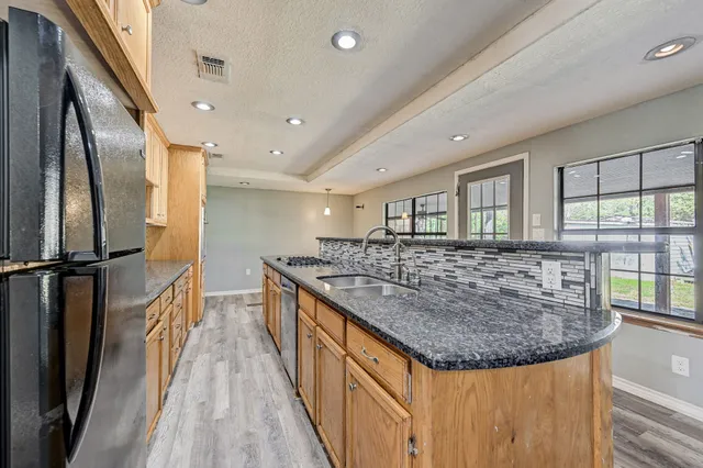 a kitchen with stainless steel appliances granite countertop a sink and a refrigerator