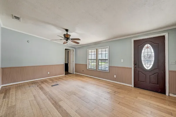 a view of an empty room with a window and wooden floor