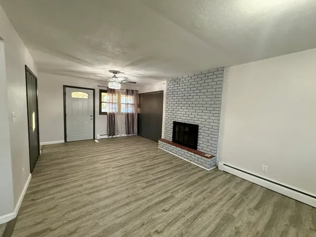 an empty room with wooden floor and fireplace