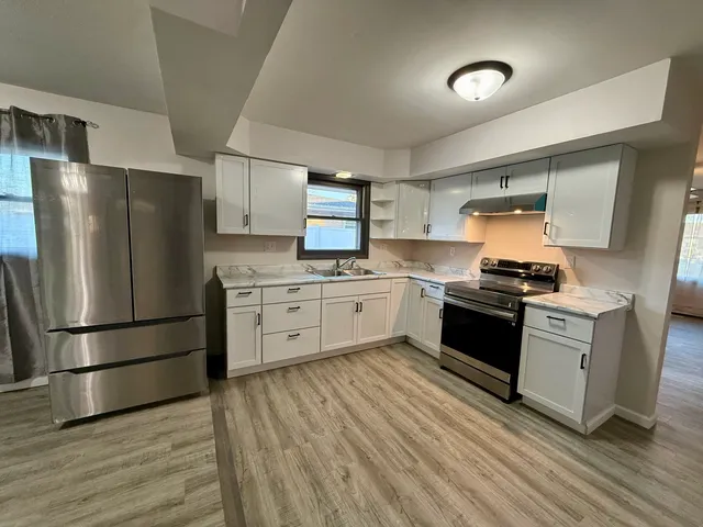 a kitchen with granite countertop a refrigerator stove top oven and sink