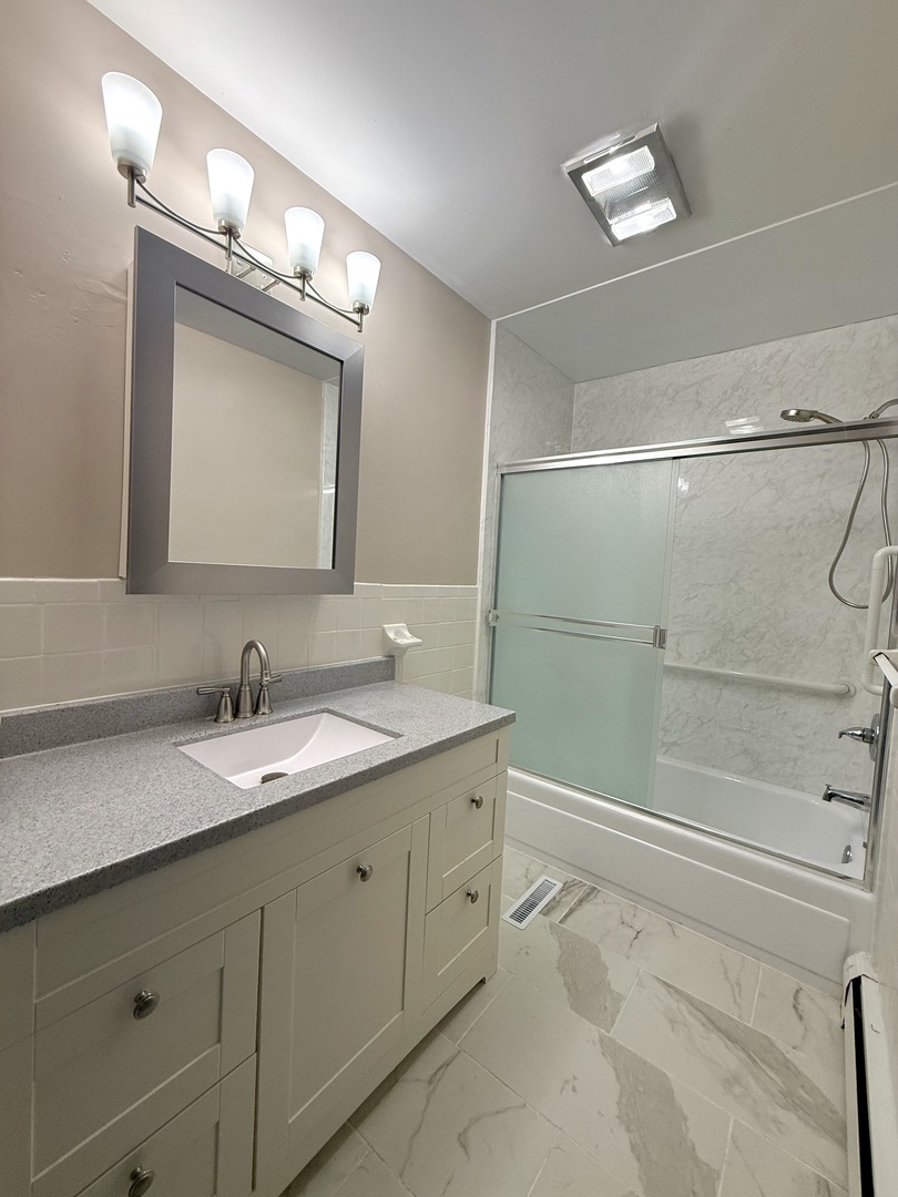 1357 Jeffrey Drive Rantoul, IL 61866 - Photo 10 of 21 a bathroom with a granite countertop sink a mirror and a shower