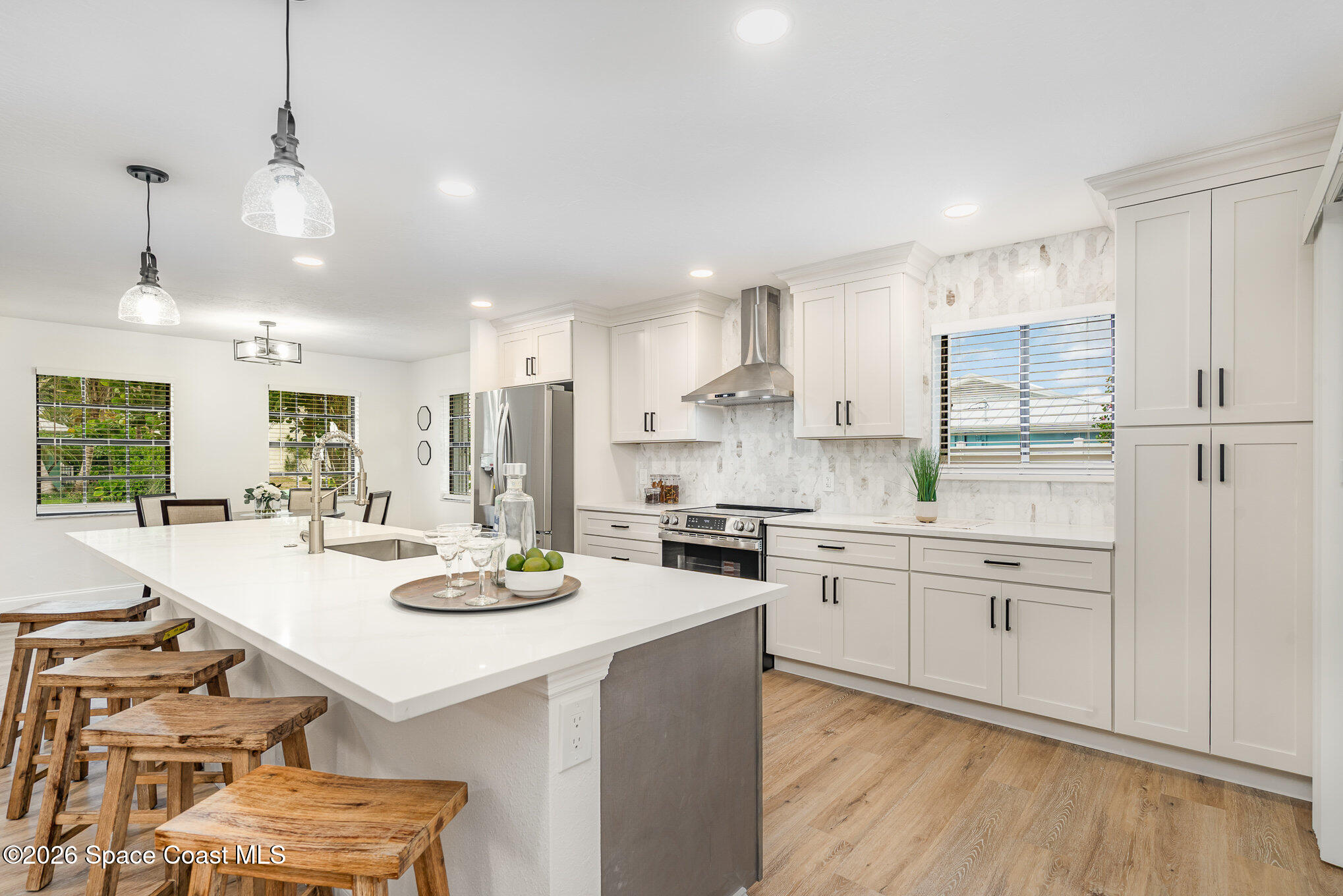 362 Nikomas Way Melbourne Beach, FL 32951 - Photo 6 of 32 a kitchen with a sink stove and white cabinets with wooden floor