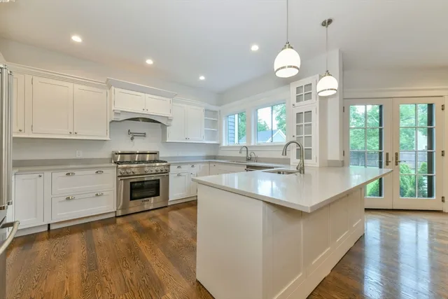 a kitchen with a stove a sink a center island and wooden floor