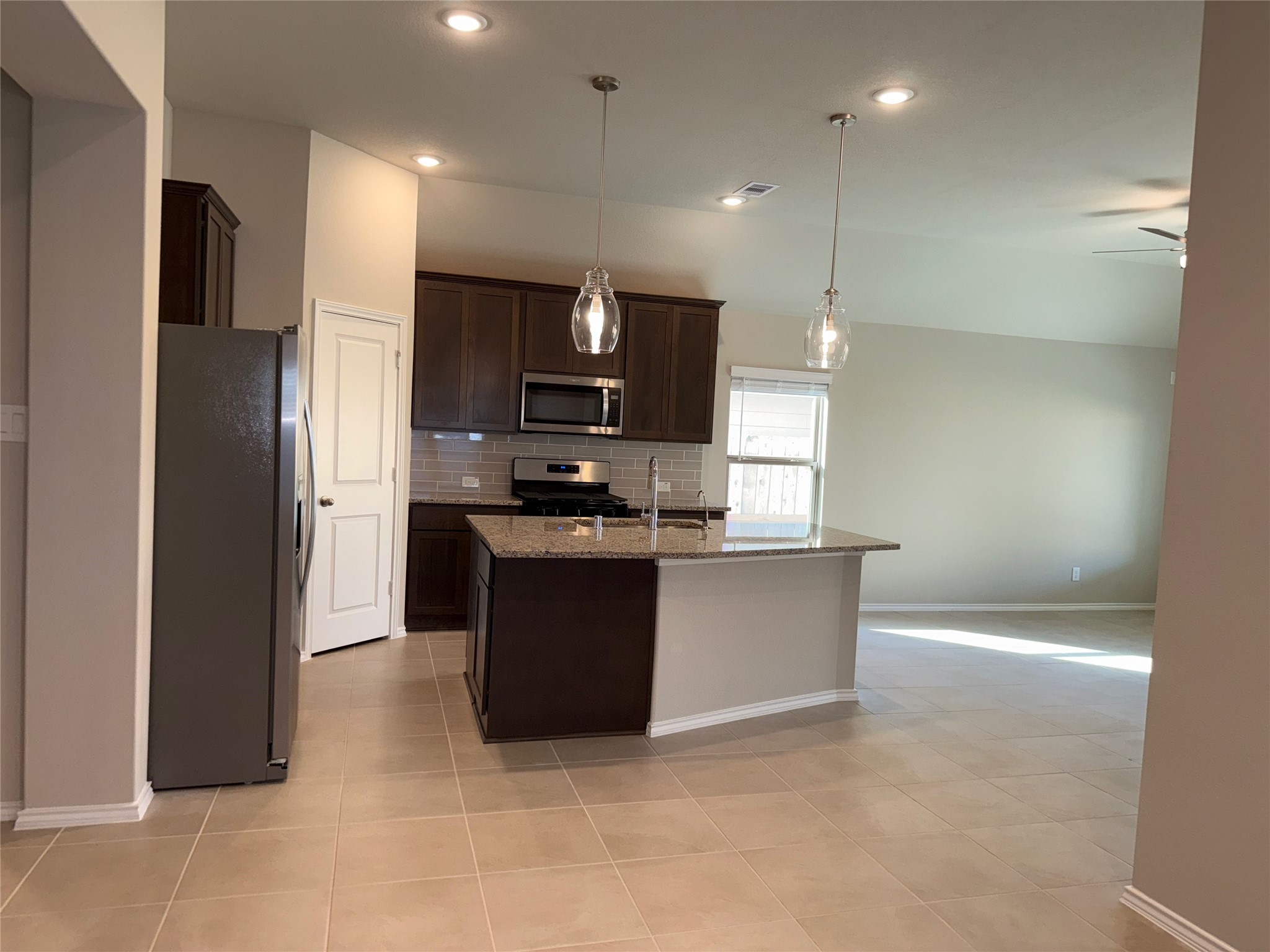 31965 Retama Rnch Drive Spring, TX 77386 - Photo 5 of 18 a kitchen with stainless steel appliances kitchen island granite countertop a refrigerator a sink and a stove