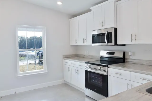 a kitchen with stainless steel appliances white cabinets and a stove top oven
