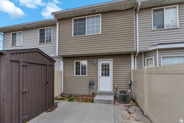 986 Independence Avenue Provo, UT 84604 - Photo 19 of 29 Rear exterior featuring two levels of siding, multiple windows, a white paneled door, and a concrete patio