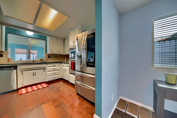 a kitchen with stainless steel appliances granite countertop a table chairs and a refrigerator