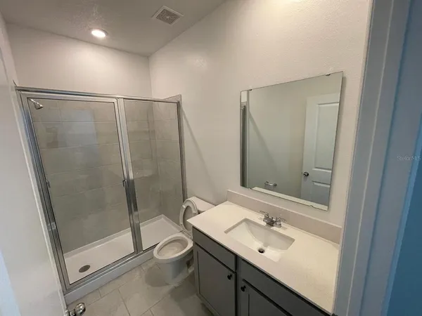 a bathroom with a shower sink mirror and toilet
