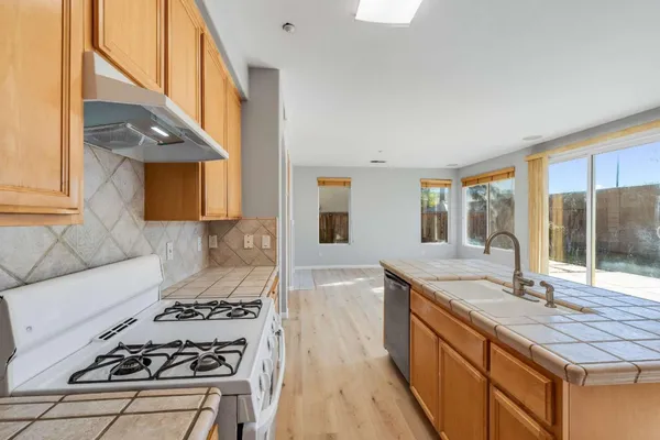 a kitchen with stainless steel appliances a stove a sink and a granite counter tops with white cabinets next to a window