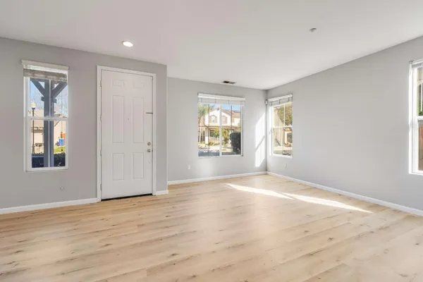a view of an empty room with window and wooden floor