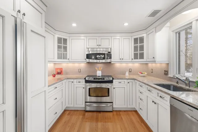a kitchen with stainless steel appliances granite countertop a stove and white cabinets