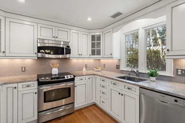 a kitchen with stainless steel appliances granite countertop a sink a stove a microwave and wooden cabinets
