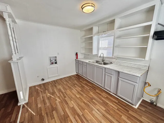 a kitchen with a sink a stove cabinets and wooden floor
