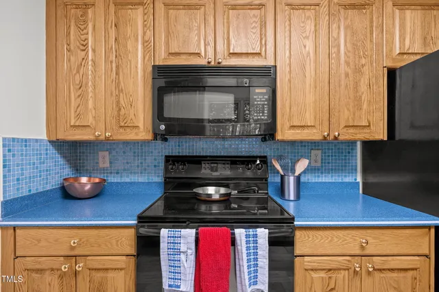 a kitchen with granite countertop a refrigerator stove and cabinets