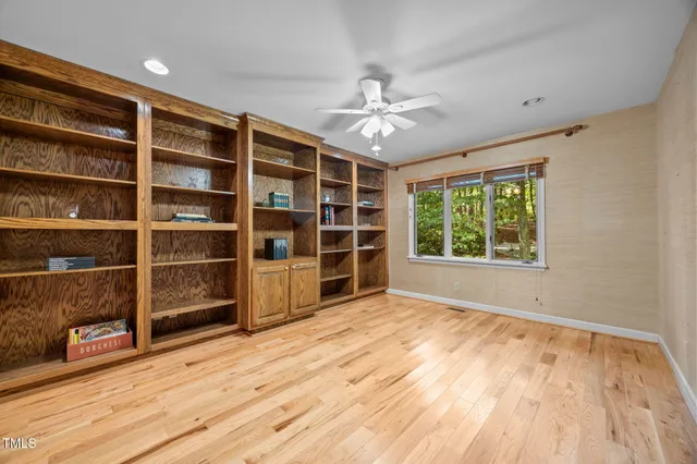 a view of empty room with wooden floor and fan
