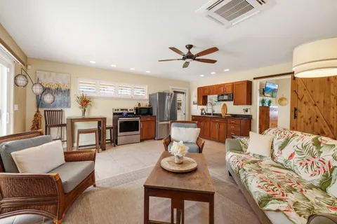 a living room with furniture kitchen view and a chandelier