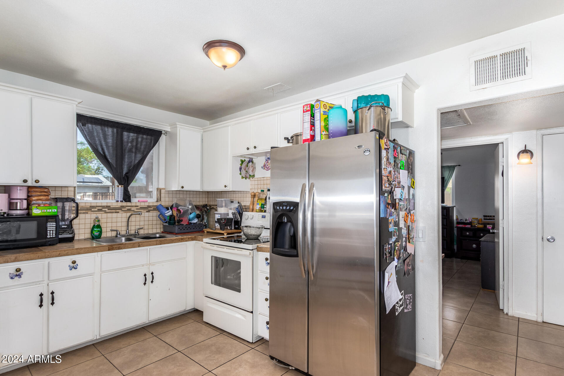 3845 North 15th Avenue Phoenix, AZ 85015 - Photo 9 of 28 a kitchen with stainless steel appliances a refrigerator sink and cabinets
