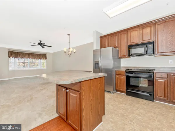 a kitchen with stainless steel appliances granite countertop a refrigerator a stove and a sink with wooden cabinets