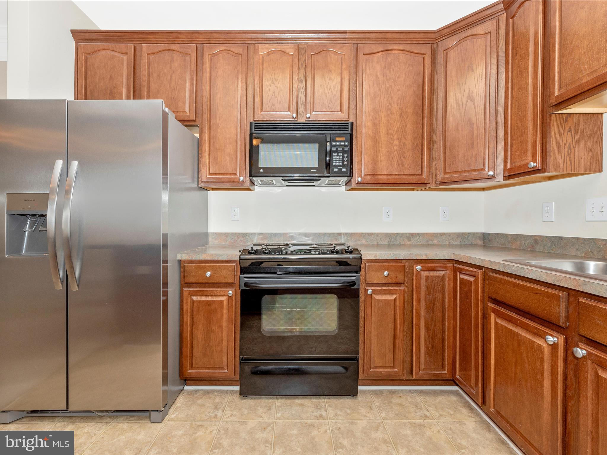 120 Burgess Hill Way, Unit 207 Frederick, MD 21702 - Photo 20 of 67 a kitchen with stainless steel appliances granite countertop a refrigerator a stove and a sink with wooden cabinets