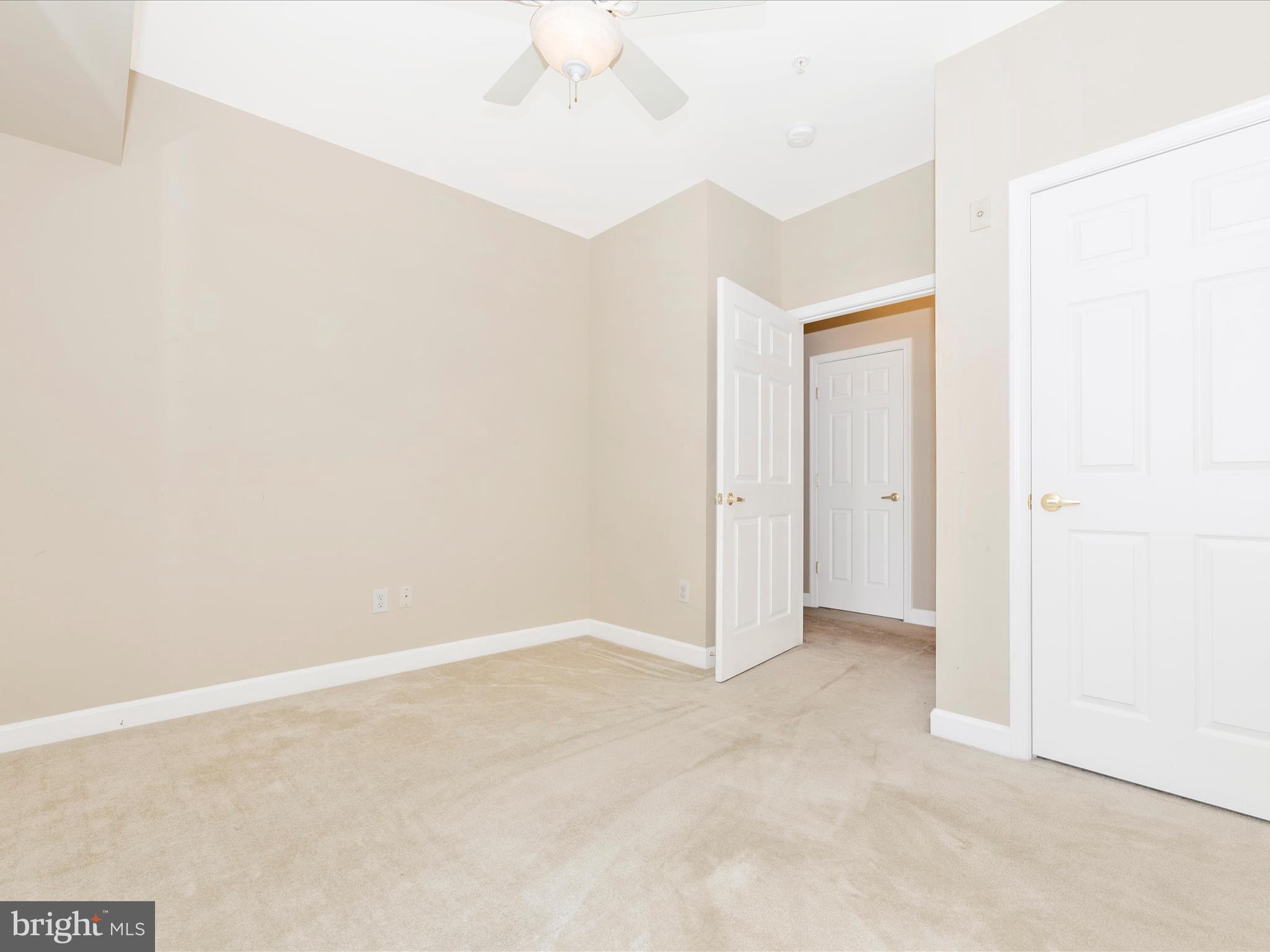 120 Burgess Hill Way, Unit 207 Frederick, MD 21702 - Photo 37 of 67 an empty room with a ceiling fan and carpet
