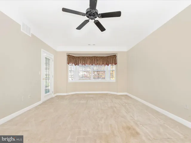 an empty room with a window and a ceiling fan