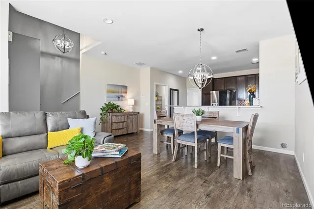 a living room with furniture dining table a rug and a chandelier